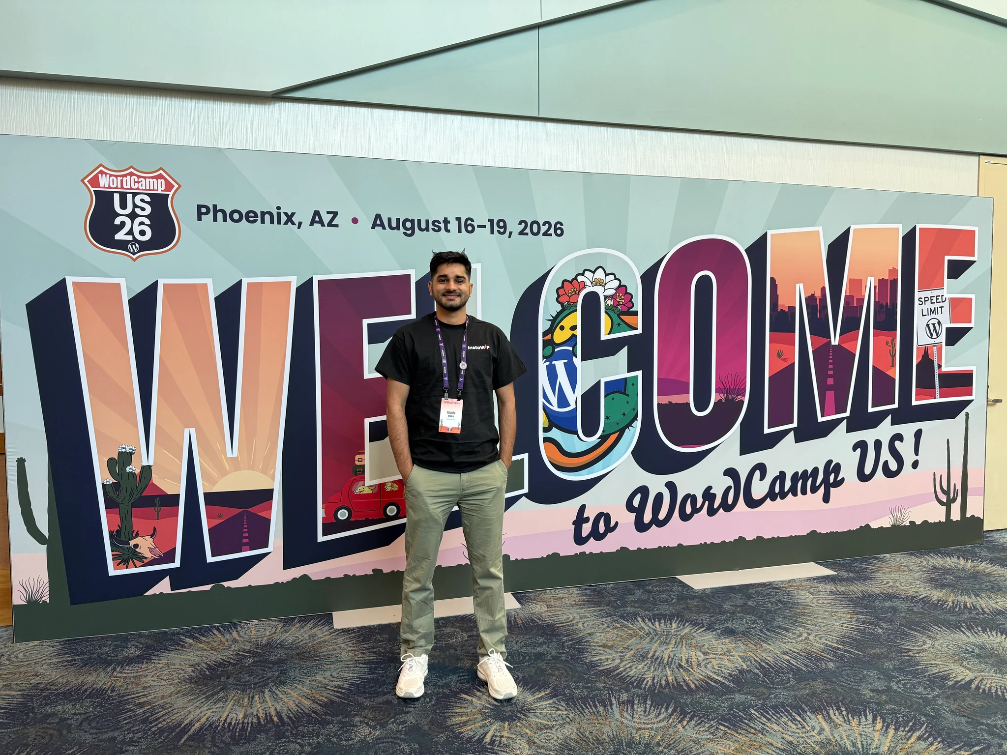 Ananta wearing the black InstaWP t-shirt with volunteer badge at the Welcome banner