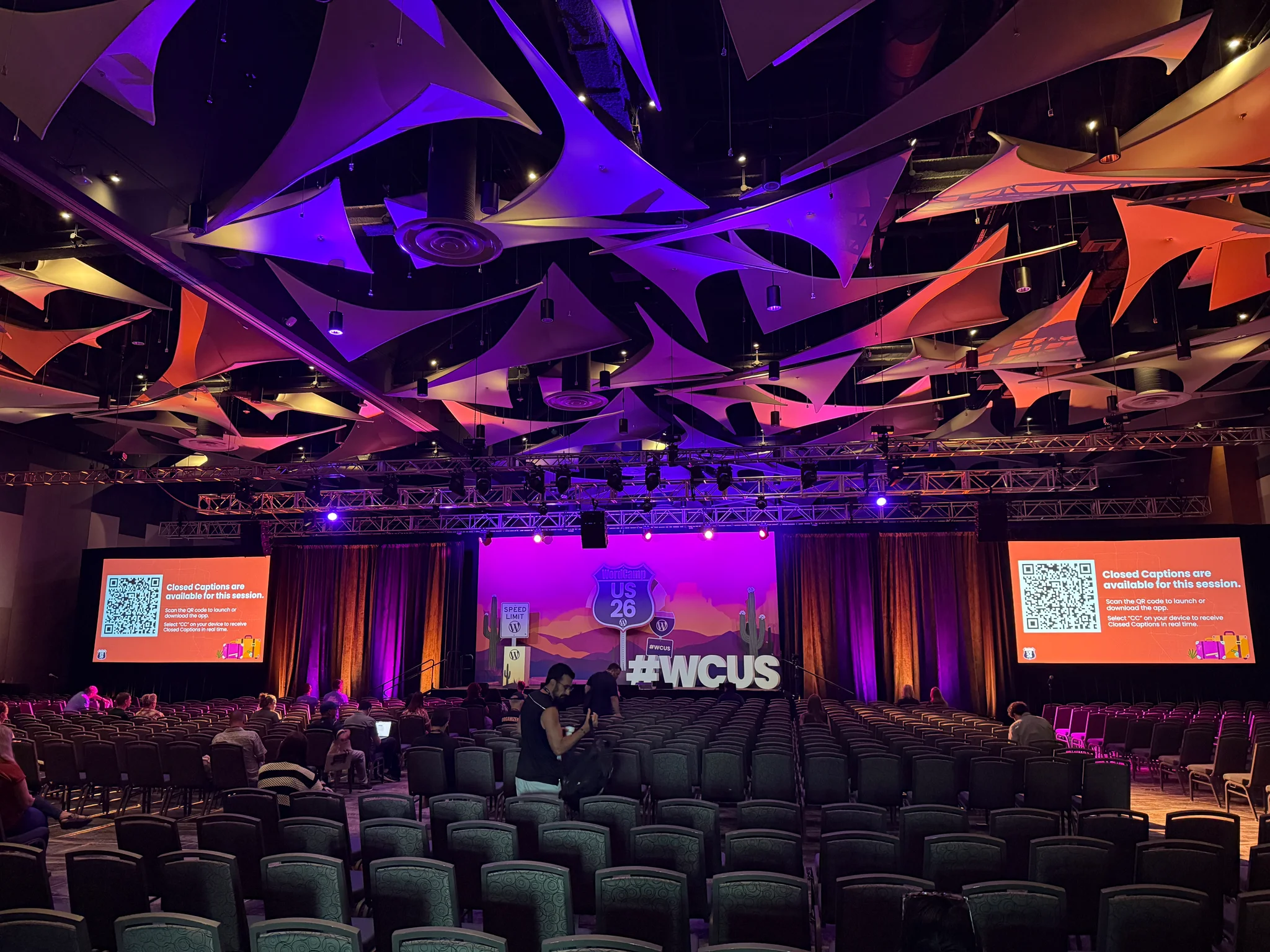 The North Ballroom stage illuminated in purple with acoustic ceiling sails and #WCUS sign