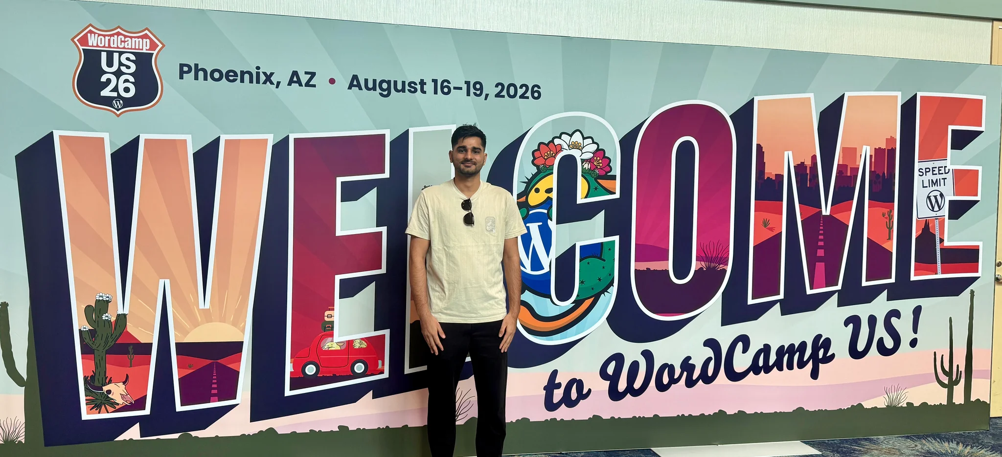 Ananta arriving on Day 0 at the giant Welcome to WordCamp US banner